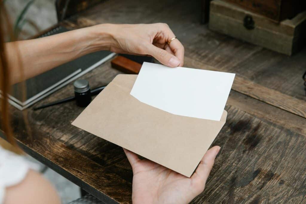 Close-up of hands holding an envelope with a letter on a rustic wooden desk, ideal for communication themes.